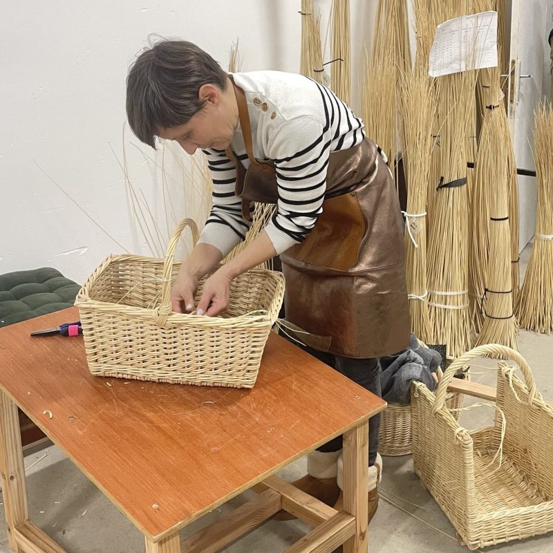 vannière courbée sur poste de travail, tissant un panier